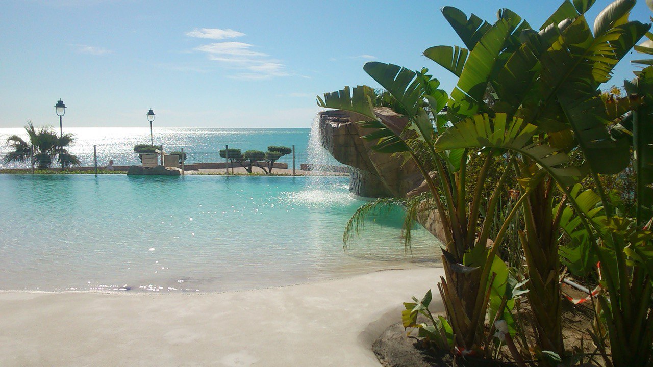 Piscina de arena tipo playa junto al mar con vegetación